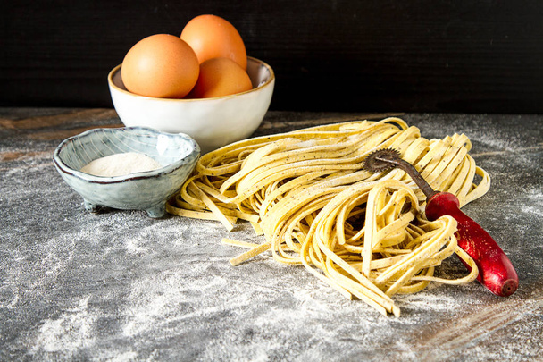 Homemade italian tagliatelle with flour. Dark background. - Foto, imagen