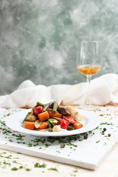 légumes grillés sur une assiette blanche sur une planche à découper sur une table en bois avec tomates cerises et légumes verts
 - Photo, image