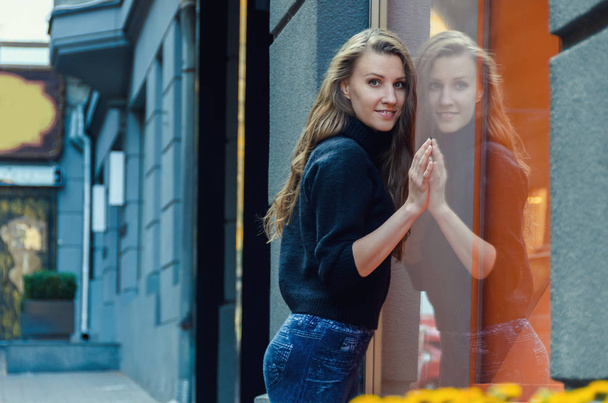 Красивая стройная женщина стоит перед витриной магазина
. - Фото, изображение