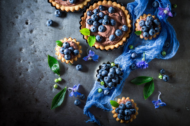 Tasty and sweet tarts with blueberries, chocolate cream and berries - Foto, afbeelding