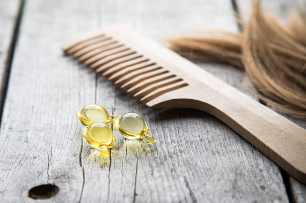 Воспитание волос. капсула витамина сыворотки на деревянном фоне
 - Фото, изображение