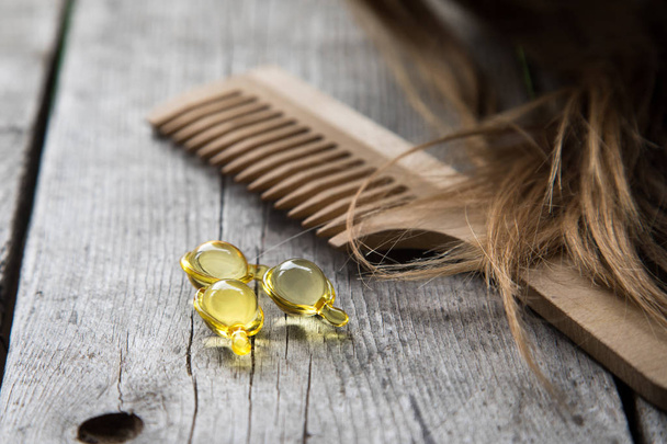 Hair nurishment. vitamin serum capsule on wooden background - Photo, Image