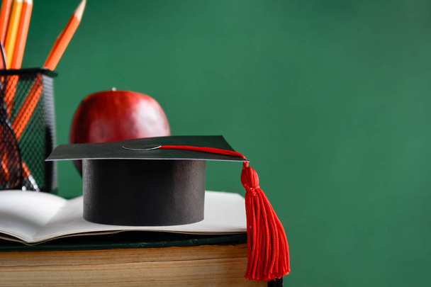 graduate cap and apple on old book at library green wall backgro - Foto, Imagen