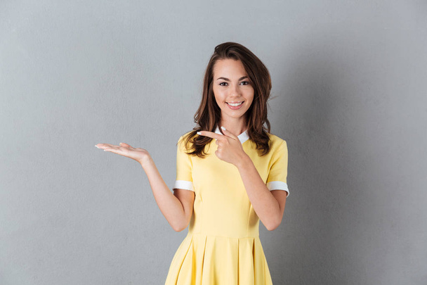 Happy girl in dress holding copy space on a palm - Fotó, kép