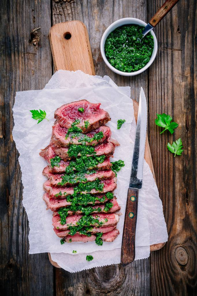 Sliced grilled barbecue beef steak with green chimichurri sauce - Photo, Image