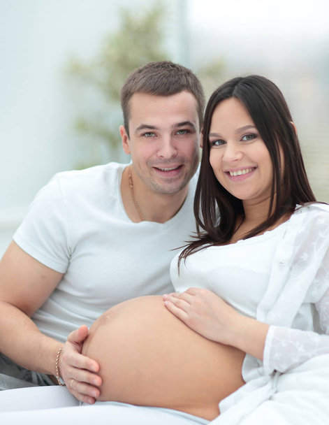 Pregnant woman with her husband relaxing at home - Foto, afbeelding