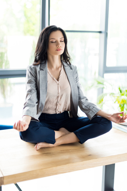 businesswoman meditating at workplace - Fotó, kép