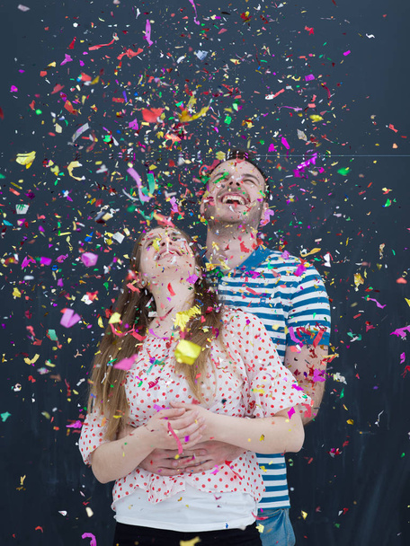couple blowing confetti in the air isolated over gray - Fotoğraf, Görsel