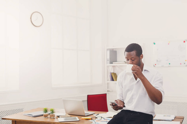 Jovem homem de negócios preto com telefone celular no escritório branco moderno
 - Foto, Imagem