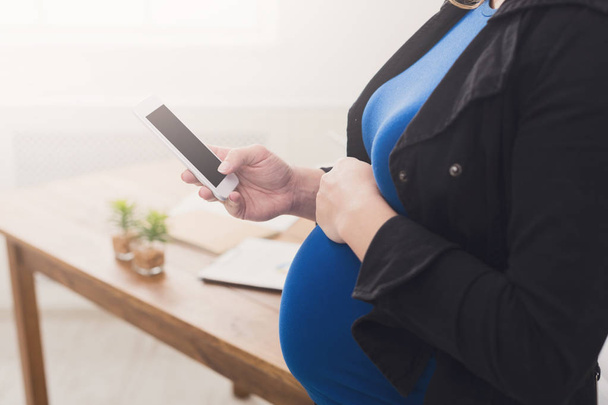 Unrecognizable pregnant woman with smartphone - Fotó, kép