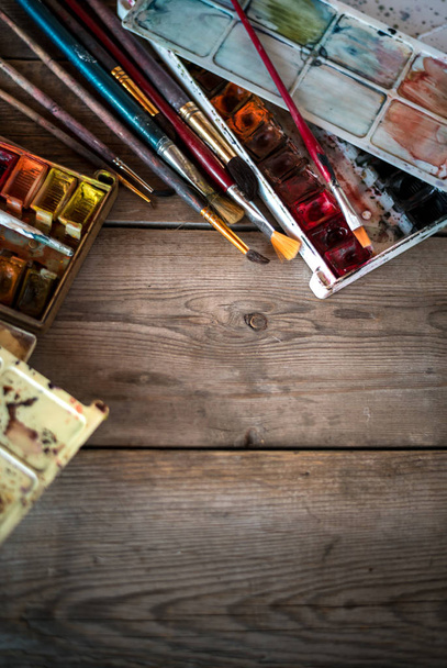 Sfondo con pennelli usati e vernici ad acquerello su vecchie tavole di legno. Posto per il testo. Vista dall'alto con spazio di copia
 - Foto, immagini