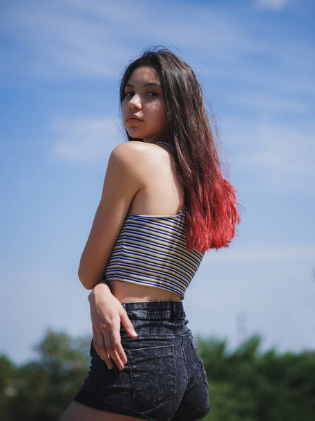 Un retrato de una hermosa adolescente con ropa de verano posando sobre un fondo natural. Moda, concepto juvenil. Copiar espacio
. - Foto, imagen