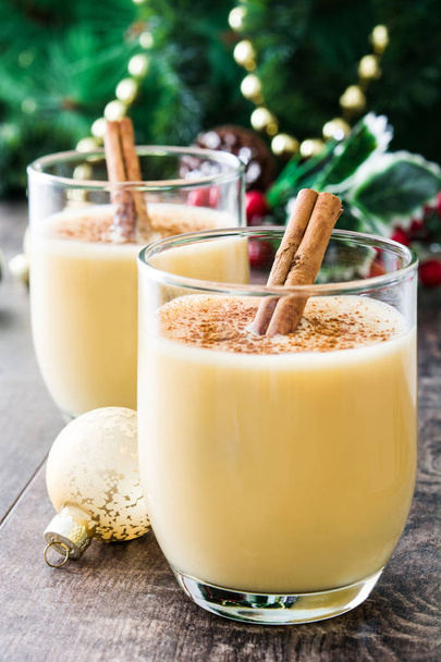 Homemade eggnog with cinnamon on wooden table. Typical Christmas dessert. - Fotó, kép