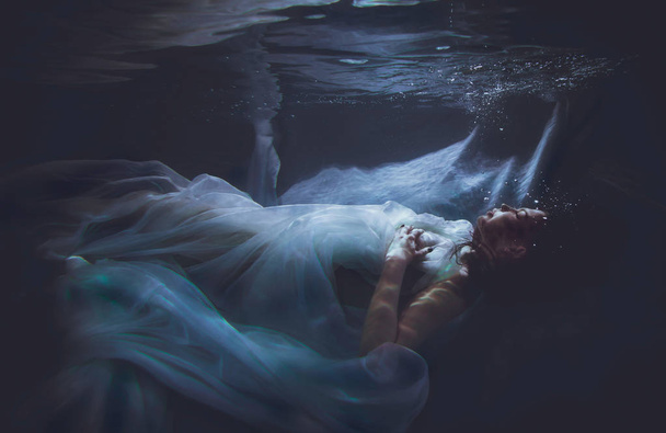 Beautiful woman swimming with fancy dress underwater - 写真・画像