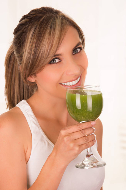 Красива молода усміхнена жінка в білій футболці і тримає здоровий салат однією рукою і склянкою соку в іншій руці
 - Фото, зображення