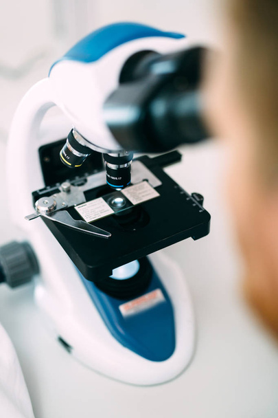 Closeup picture of researcher looking through microscope - Photo, image
