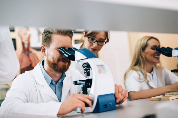 Group of scientists doing research looking through microscope - Photo, image