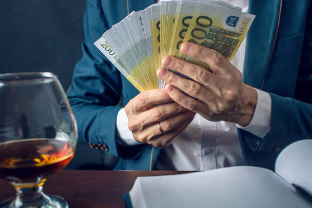 Бізнесмен людина в костюмі кладе гроші в свою кишеню. Хабар у вигляді законопроектів євро. Концепція корупції та хабарництва - Фото, зображення