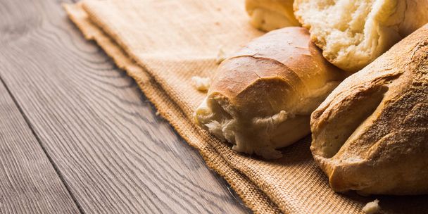 Freshly baked bread on burlap dark wooden background - Foto, Bild