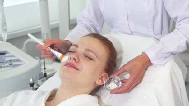 Cosmetologist εφαρμόζεται κρέμα στο πρόσωπό τους πελάτες - Πλάνα, βίντεο