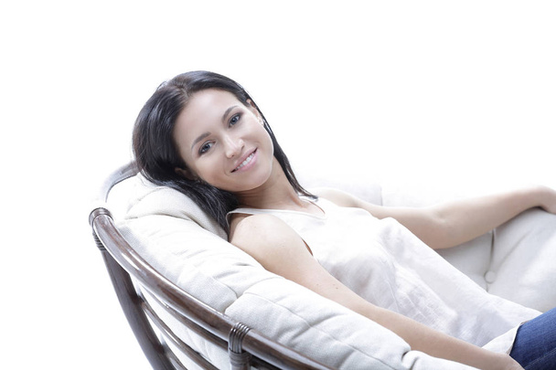 Modern young woman relaxing in a round cozy soft chair - 写真・画像