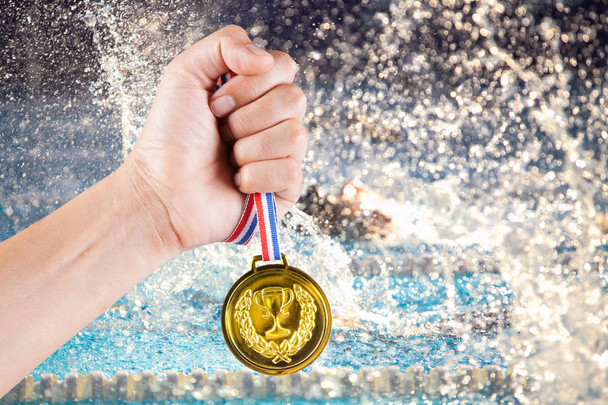 punhado de ásia homem segurando ouro medalha com embaçado fundo de natação piscina e competição
. - Foto, Imagem