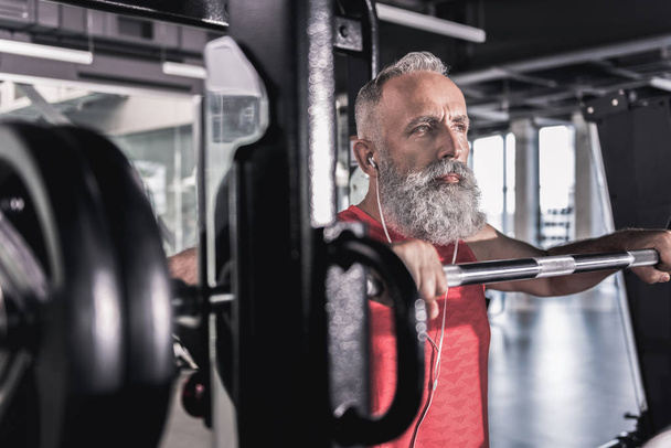 Pensive serious male with beard enjoying workout in athletic center - Zdjęcie, obraz