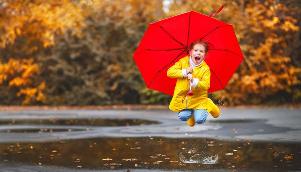 happy child girl with an umbrella and rubber boots in puddle  on - Photo, Image
