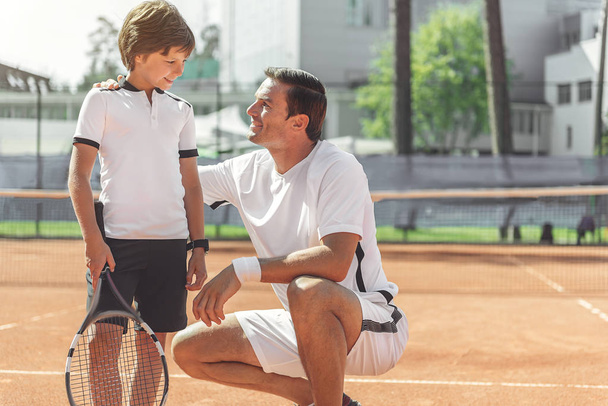 Szczęśliwy uśmiechający się chłopiec Spojrzawszy trener tenisa - Zdjęcie, obraz
