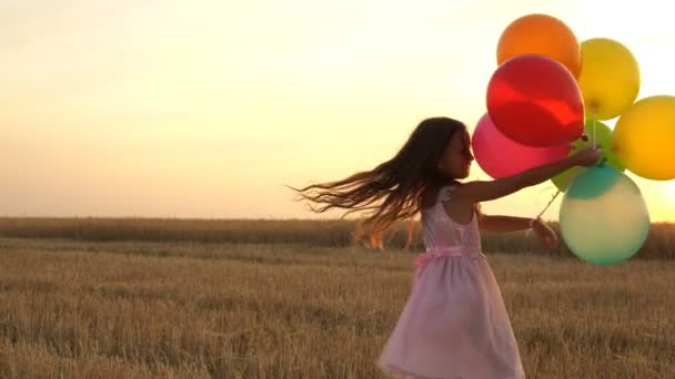 girl walking in a field with balloons - Záběry, video