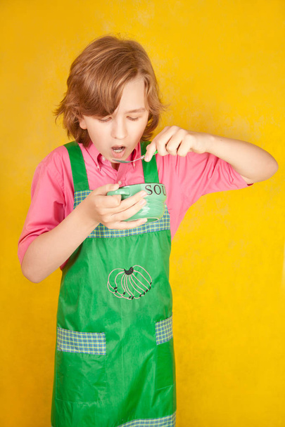 ωραίο είδος έφηβο, τρώει σούπα σε φόντο κίτρινο studio μόνο - Φωτογραφία, εικόνα