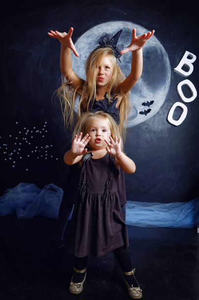 Two cute little sisters are dressed in witch costumes - Fotoğraf, Görsel