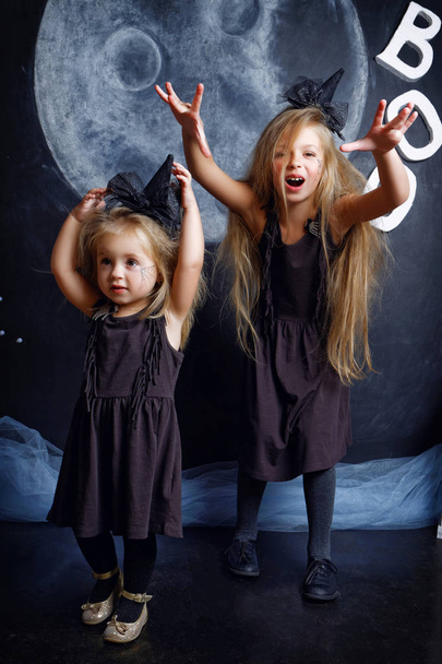 Two cute little sisters are dressed in witch costumes - Foto, Imagen