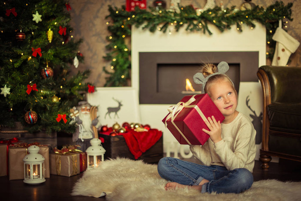Christmas. Small girl is holding the box with gifts on christmas - Photo, Image