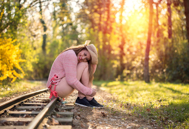 Gorgeous young woman sitting on a railway - Foto, Bild