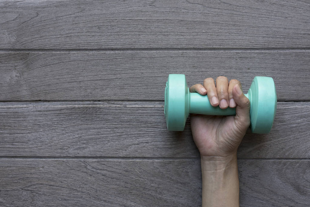woman hand holding green dumbbell on wood table background - Fotó, kép
