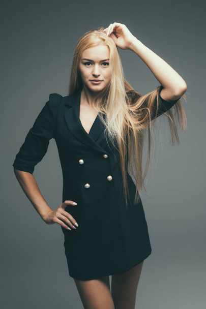 Kaunis seksikäs nainen vaaleat hiukset kulumista mekko takaisin rento katu tyyli malli suunnittelija harmaa tausta
 - Valokuva, kuva