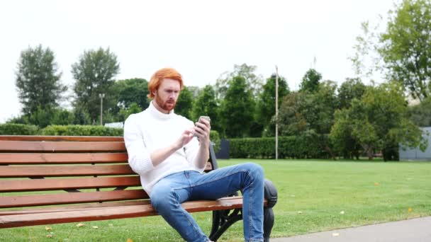 Meghibásodás, veszteség gesztus használ Smartphone, szabadtéri padon ülő ember - Felvétel, videó
