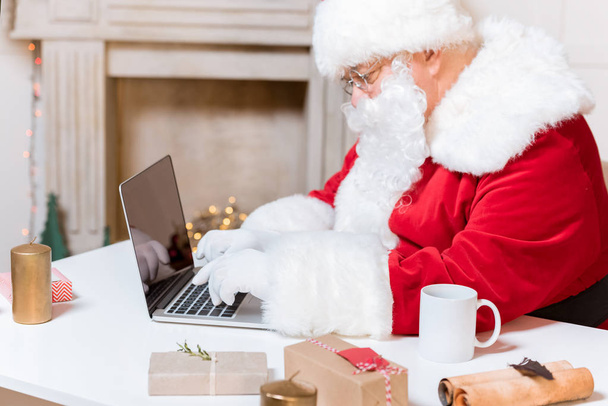 Santa Claus escribiendo en el ordenador portátil
 - Foto, Imagen