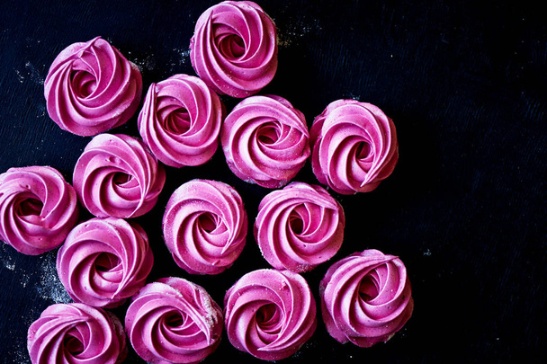 Many purple marshmallow on a dark surface. A contrasting picture. A work of culinary art - Fotoğraf, Görsel