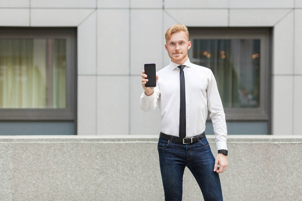 Success business man showing new smart phone and looking at camera. - Fotó, kép