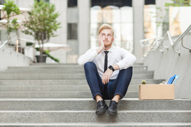 Unfair ginger young adult worker sit on stairs and wondering. - Photo, Image