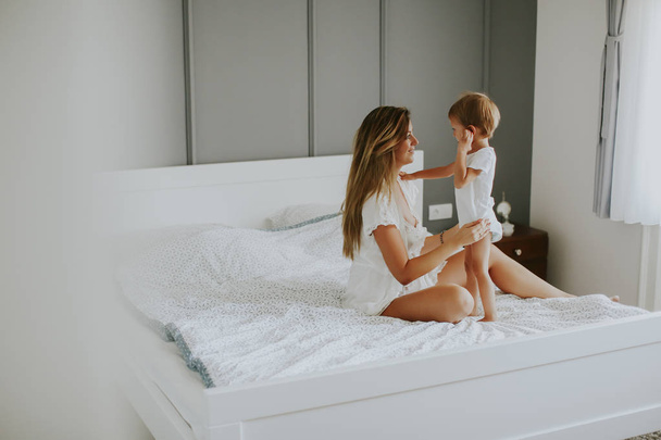Mother playing with little boy on the bed in the room - Foto, Bild