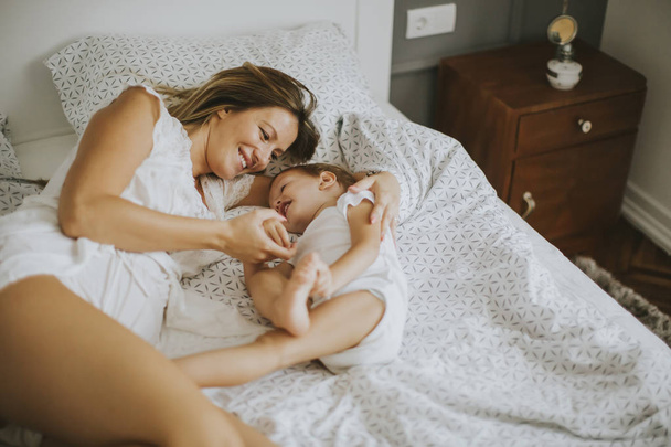 Moeder spelen met kleine jongen op bed - Foto, afbeelding