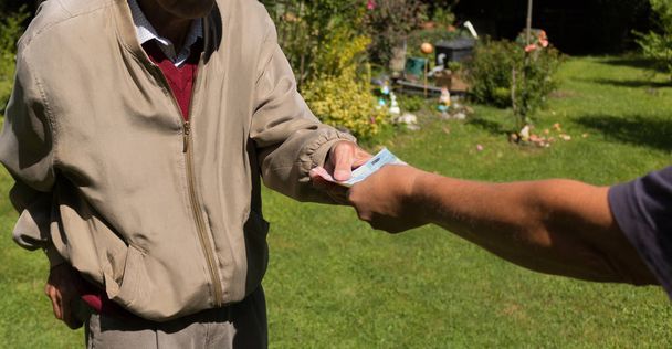 Les mains d'un senior tenant un billet en euros. Pensionnés en difficulté
  - Photo, image