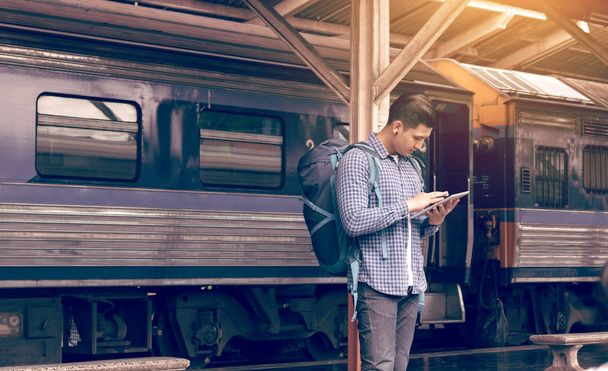 Hombre asiático mochila para viajar en la estación de tren y el uso de la tableta
  - Foto, imagen