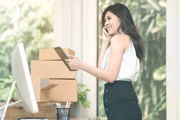 Młody przedsiębiorca sprawdzanie stanów magazynowych produktów na smart tabletka podczas rozmowy z jej w domu klienta pakietu office - Zdjęcie, obraz