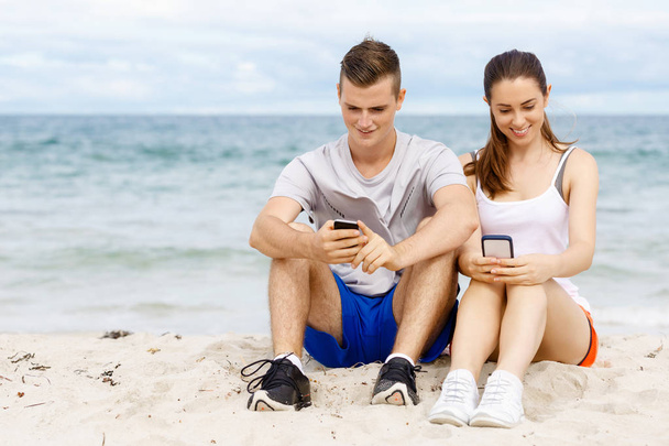 Couple of runners with mobile smart phones outdoors - Фото, изображение