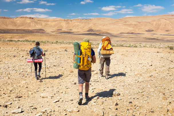 Três mochileiros caminhando trilha deserto de pedra
.  - Foto, Imagem