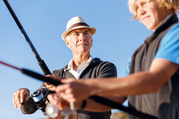 Senior man fishing with his grandson - Photo, Image